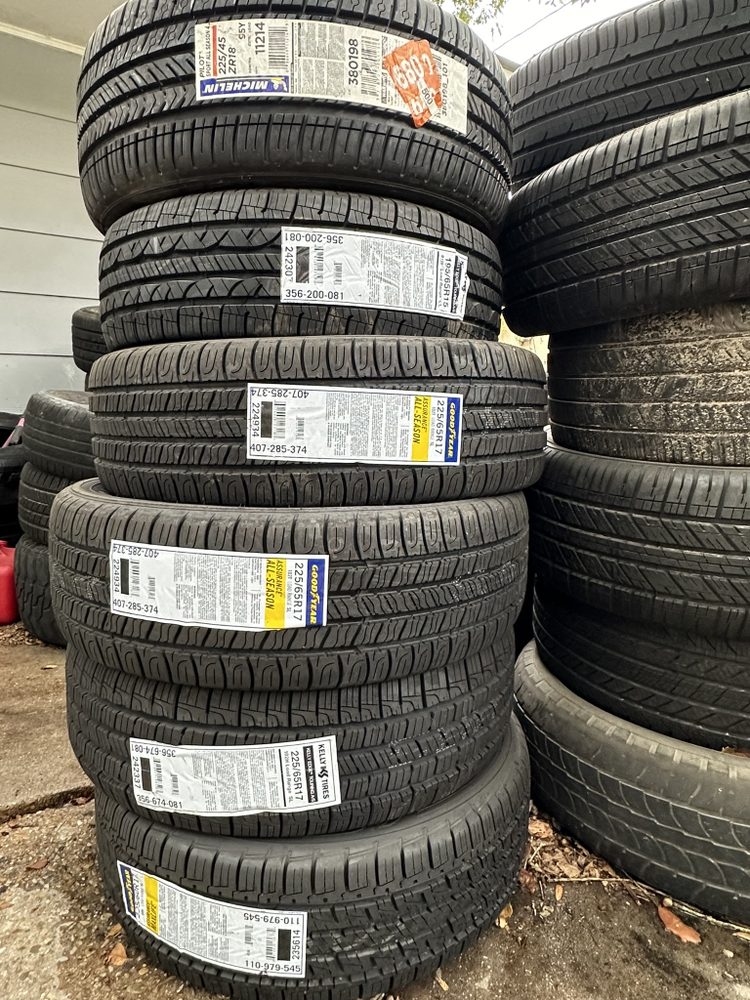 Stacks of new tires with factory labels standing on a concrete pad